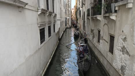 Line-Of-Gondolas-Carrying-Tourists-And-Holiday-Makers-Going-Past-Along-Narrow-Venice-Canal