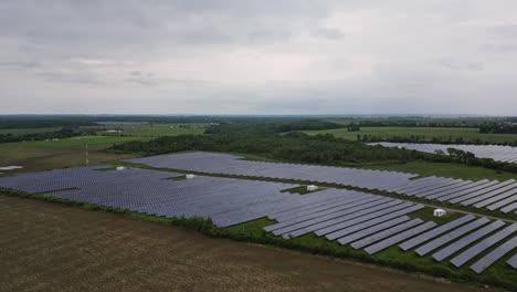 Photovoltaic-Solar-Panels-On-Green-Field-On-A-Cloudy-Day---drone-shot