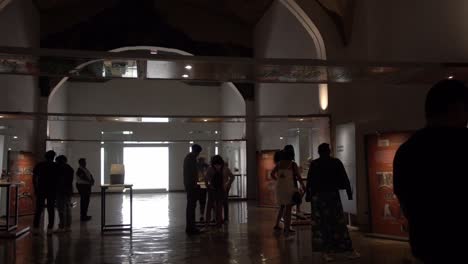 A-cinematic-low-angle-wide-view-of-some-people-gathered-inside-a-hall-of-a-museum