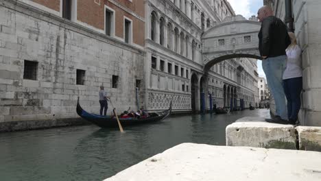 Tourists-Watching-Gondolas-Go-Past-Along-Towards-Bridge-Of-Sighes-On-Rio-del-Palazzo-In-Venice