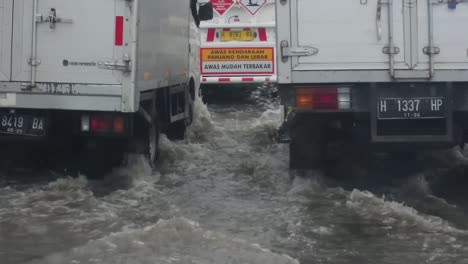 Box-truck-vehicles-pass-through-tidal-floods-in-the-city-of-Semarang,-Central-Java,-Indonesia
