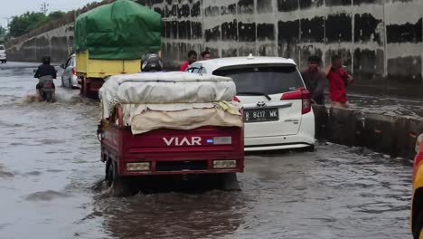 Menschen-Und-Einige-Fahrzeuge-Fahren-Durch-Flutfluten-In-Der-Stadt-Semarang,-Zentral-Java,-Indonesien