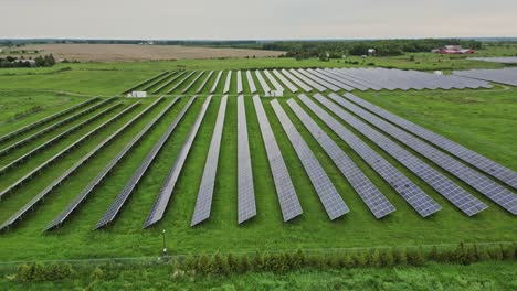 Solar-Panels-On-Green-Grass-Field---aerial-drone-shot
