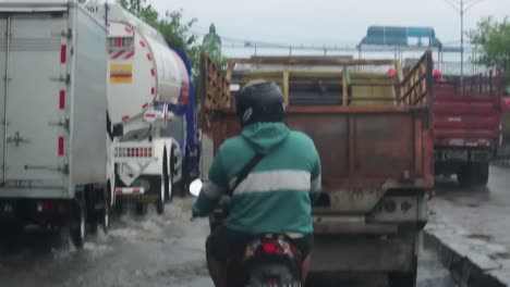 Some-Vehicles-pass-through-tidal-floods-in-the-city-of-Semarang,-Central-Java,-Indonesia