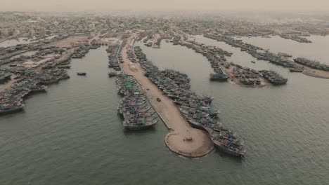 Aerial-Birds-Eye-View-Of-Fishing-Boats-Moored-Along-Jetty-At-Ibrahim-Hyderi-In-Karachi