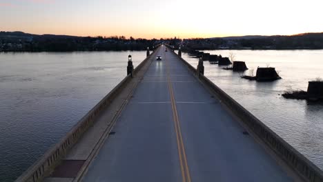 Aerial-view-of-vehicles-driving-on-Suspension-bridge-between-Columbia-and-Wrightsville-borough-during-sunset-time---Wide-shot