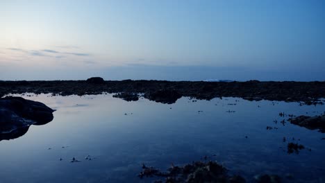 Flachwinkel-Rutschaufnahme-Nach-Rechts-Während-Eines-Wunderschönen-Sonnenuntergangs-Bei-Ebbe-Auf-Bali,-Indonesien,-Wobei-Sich-Der-Horizont-Im-Kristallklaren-Wasser-Spiegelt