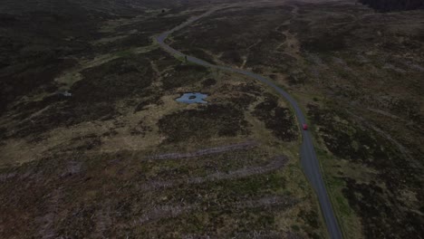 Late-evening-red-car-is-captured-by-drone-driven-along-single-track-road