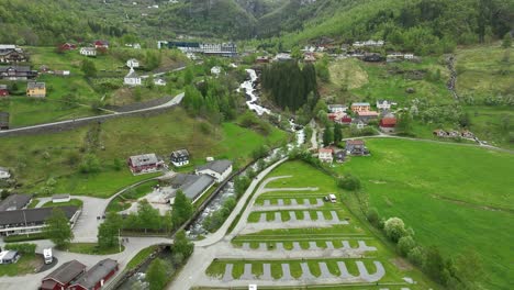 Geiranger-camping-beside-road-and-river-with-Hotel-Union-in-background---Forward-moving-rising-aerial