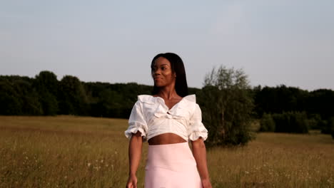 Happy-black-woman-walking-in-summer-field-during-sunset-enjoying-the-warm-weather