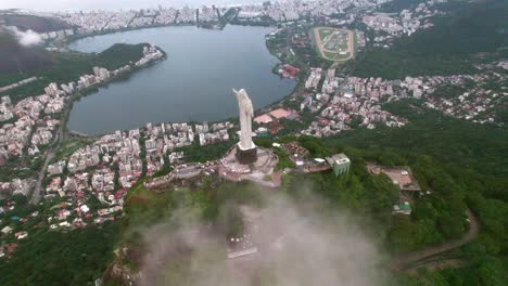 Toma-Aérea-En-órbita-De-Cristo-Redentor-Con-La-Laguna-Rodrigo-De-Freitas-Al-Fondo,-Río-De-Janeiro