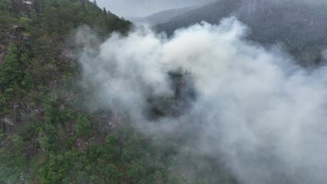 Forest-fire-just-started-after-lightning-strike-in-green-dry-hillside-of-Norway-Mountain---Aerial-showing-fire-with-smoke-blowing-towards-camera