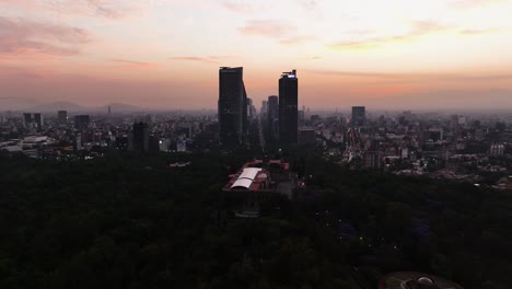 Drone-shot-over-the-Chapultepec-castle-toward-downtown-skyscrapers,-dusk-in-Mexico-city