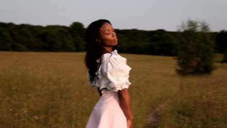 Black-woman-turns-head-looking-back-at-sunset-standing-in-field-during-a-warm-sunny-day
