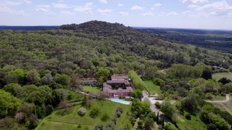 Aerial-over-natural-landscape-and-house-with-swimming-pool-in-the-middle-of-forest,-located-at-Saint-Victor-des-Oules,-southern-France