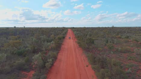 Drone-shot,-The-back-of-a-car-driving-down-a-long-desert-road
