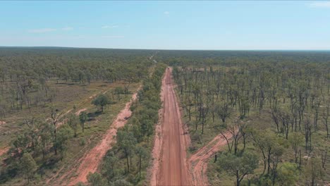 Drohnenschuss,-Roter-Feldweg-Im-Australischen-Wüstenoutback,-Gesäumt-Von-Bäumen