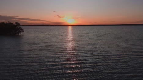 Wunderschöner-Orange-Leuchtender-Sonnenuntergang,-Der-Sich-Im-Meerwasser-Spiegelt-Und-Vorbeifliegende-Vögel