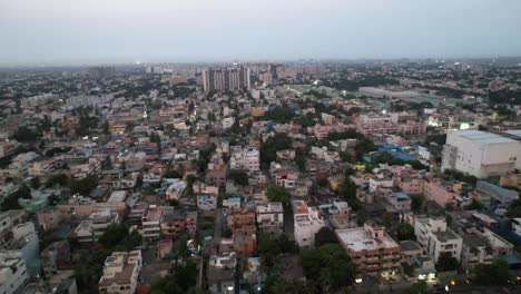 A-crowded-neighborhood-in-Chennai-City-is-seen-from-above-in-the-evening,-along-with-high-rise-buildings-and-metro-rail-construction