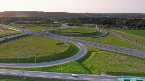 Aerial-establishing-shot-of-new-modern-intersection-highway-with-bridge-in-green-scenery-at-golden-sunset