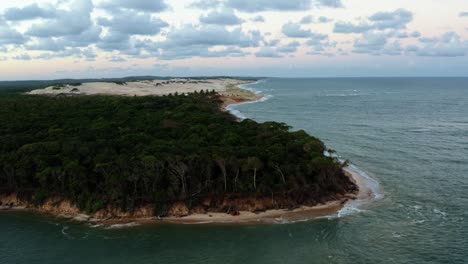 Right-trucking-aerial-drone-shot-of-the-tropical-Malembá-beach-with-dense-jungle-and-golden-sand-dunes-where-the-Guaraíras-Lagoon-meets-the-Atlantic-Ocean-in-Tibau-do-Sul,-Rio-Grande-do-Norte,-Brazil