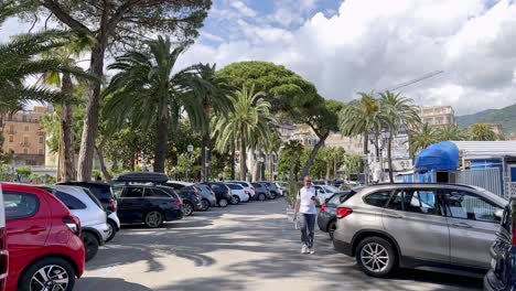 Car-park-in-Rapallo,-Laguna-shaded-with-beautiful-trees-and-palm-trees-while-pedestrian-is-walking