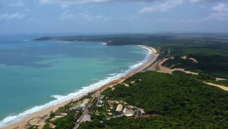 Tilting-up-aerial-drone-extreme-wide-shot-of-the-famous-tropical-Northeastern-Brazil-coastline-with-the-tourist-town-of-Pipa-in-the-background-and-beaches-surrounded-by-cliffs-in-Rio-Grande-do-Norte