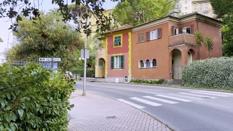 A-street-in-Rapallo-with-old-colourful-villas,-a-scooter-or-moped-and-pedestrian,-Italy