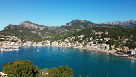 Dramatic-aerial-reveal-of-the-bay-of-Soller-Port-on-tropical-Spanish-Island-on-hot-sunny-summer-day-with-clear-blue-sky