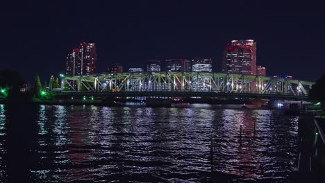 Night-light-Tokyo,-Tsukuda,-Toyosu-skyscrapers-and-bridge-the-Sumida-River-Yakatabune,-pleasure-boat