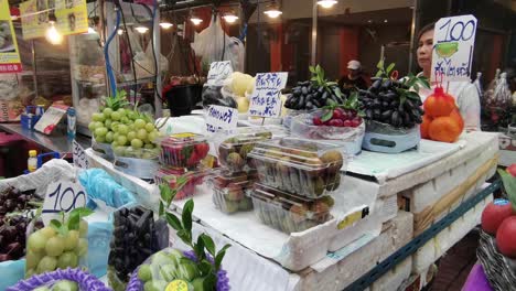 Eine-Verkäuferin-Zieht-Einen-Großen-Stand-Voller-Weintrauben-Und-Anderen-Frischen-Früchten-In-Bangkoks-Chinatown