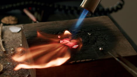 Jeweler-melting-silver-metal-blow-torch-workshop-open-flame-wood-desk