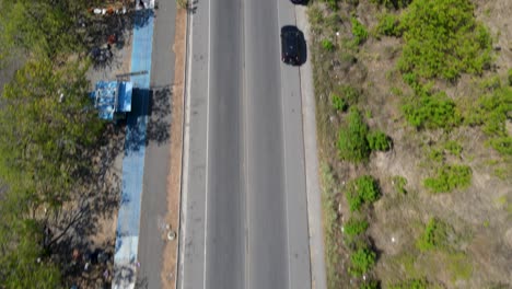 Aerial-drone-view-revealing-the-highway-traffic-in-Port-Caldera-next-to-the-coast,-Puntarenas,-Costa-Rica