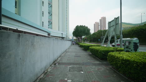 Shot-of-people-walking-on-sidewalk-by-the-roadside,-Hong-Kong,-China