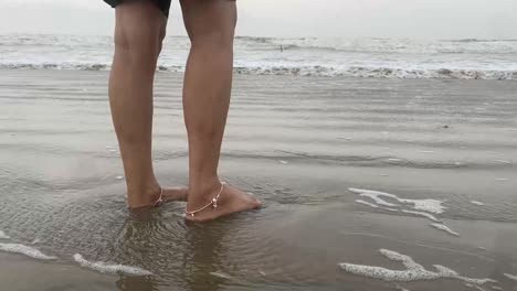 Wellen-Schlagen-Auf-Die-Beine-Eines-Indischen-Mädchens,-Das-Am-Strand-Steht