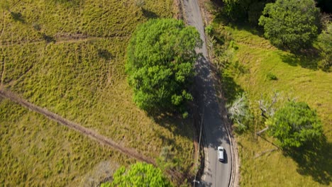 Aerial-drone-shot-following-an-suv-car-driving-through-a-rural-road,-Costa-Rica