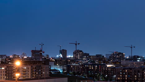 Timelapse-of-lightning-flashes-over-illuminated-city-skyline-and-cranes-at-night