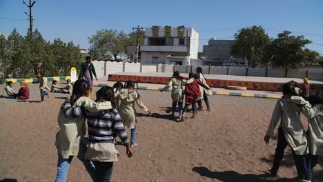 Girls-of-a-government-primary-school-are-playing-a-game-of-walking-in-which-they-have-to-walk-forward-by-supporting-each-other