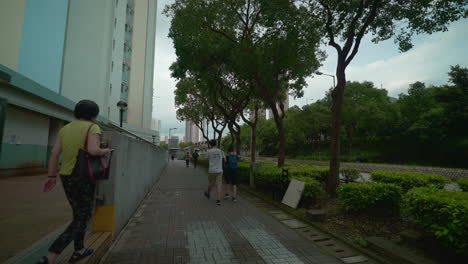 Shot-of-people-walking-on-sidewalk-by-the-roadside,-Hong-Kong,-China