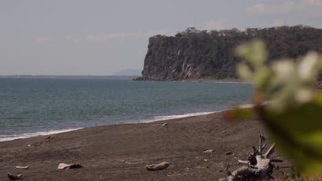 Blaues-Wasser,-Dunkler-Sand,-Leerer-Strand-Voller-Äste,-Puerto-Caldera,-Costa-Rica