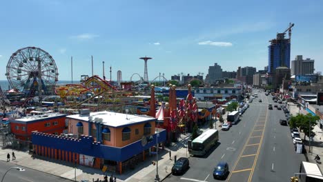 Una-Colorida-Vista-Aérea-De-La-Carretera-Que-Se-Acerca-Al-Parque-De-Diversiones-Coney-Island-En-La-Ciudad-De-Nueva-York-Con-Una-Vista-De-La-Noria-Y-El-Océano-Al-Fondo