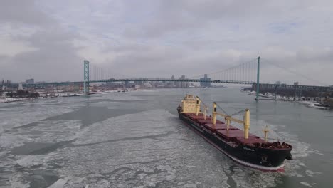 Freighter-sailing-down-icy-Detroit-River-with-city-skyline-in-background