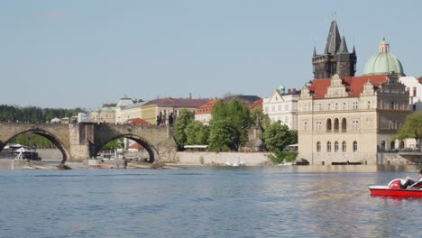 Tourists-paddling-on-the-river-Vltava-with-the-view-of-the-Iconic-Charles-Bridge-and-Old-Town-water-plant-tower-in-the-background,-Prague,-Czech-Republic