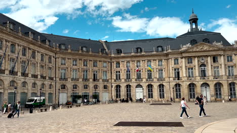Schwenkaufnahme-Des-Wunderschönen-Historischen-Place-De-La-Bourse-Und-Des-Alten-Gebäudes-In-Bordeaux-An-Einem-Sonnigen-Tag---Touristen,-Die-Im-Sommer-Am-Platz-Vorbeikommen---Zeitlupe