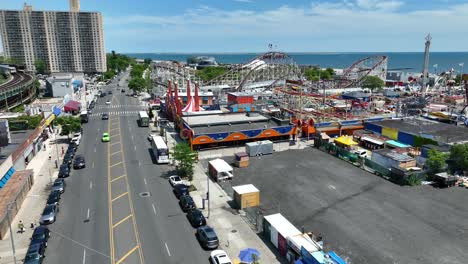 An-establishing-shot-of-Coney-Island-amusement-park-in-New-York-over-the-road-with-the-view-of-the-bay-and-cityscape-in-the-background