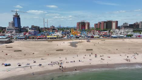 Eine-Langsame-Schwenkaufnahme-Des-Brighton-Beach-Und-Der-Promenade-Von-Coney-Island-Mit-Der-Skyline-Von-New-York-City-Im-Hintergrund