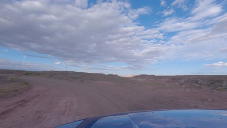Driving-along-a-dirt-road-in-a-arid-desert-landscape---driver-point-of-view-at-daytime