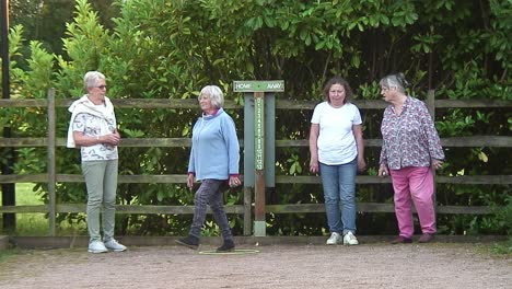 Vier-Damen-Treten-Gegeneinander-An-Und-Spielen-Die-Französische-Sportart-Pétanque,-Bei-Der-Sie-Jeweils-Ihre-Kugeln-Auf-Einen-Kleinen-Kokon-Werfen-Und-Versuchen,-Diesem-So-Nahe-Wie-Möglich-Zu-Kommen