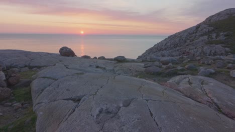 Eine-Felsskulptur,-Die-Auf-Der-Spitze-Eines-Berges-Errichtet-Wurde-Und-Einen-Blick-Auf-Das-Ruhige-Meer-Mit-Einem-Wunderschön-Satten-Rosafarbenen-Sonnenuntergang-Und-Klarem-Himmel-Bietet