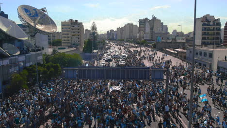 Aerial-shot-of-highway-crowded-with-Argentinian-football-soccer-fans-during-world-cup-celebration,-they-take-pictures-and-wave-flags-joyfully